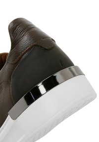 Brown leather sneaker with a black synthetic heel, metallic accent band, and a white rubber sole. Features smooth texture and a rounded toe.