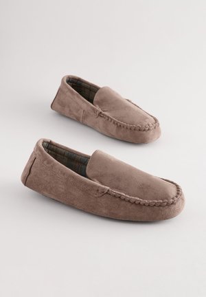 Chaussons mocassins en daim marron avec une texture douce, design à enfiler, détails de couture le long des bords, et doublure en tissu à carreaux.