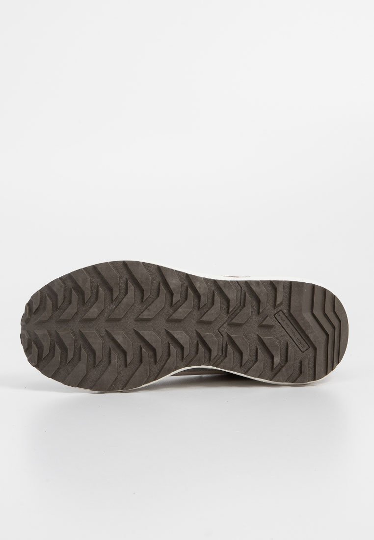 Sole di una scarpa caratterizzata da un materiale in gomma marrone con un design a profondi intagli, inclusi zig zag e caratteristiche di trazione. Bordi lisci e design pulito.