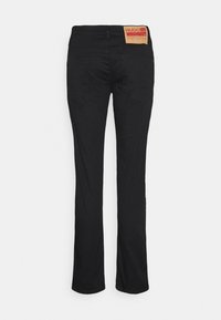 Jean noir droit avec deux poches arrière et une étiquette marron de la marque Hugo sur la ceinture, sur fond blanc.