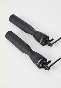 Μαύρος σχοινί άλματος με υφασμάτινες, ραβδωτές λαβές από καουτσούκ και στέρεο καπάκι από πλαστικό. Διαθέτει λεπτό καλώδιο για άλμα. Ορατό λογότυπο της μάρκας.