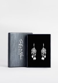 Silverhängande örhängen med intrikata cirkulära mönster, pärlor och diamantformade detaljer, presenterade i en svart sammetklädd box.