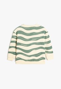 Sudadera cremosa con rayas verdes onduladas, cuello redondo y puños de canalé. Tejido suave con un patrón impreso y corte relajado.
