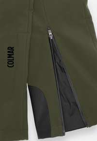 Olivgrüne Jacke mit schwarzem Reißverschlussventil, das teilweise geöffnet ist, und schwarzem, verstärktem Patch nahe dem Saum. Das "COLMAR"-Logo vertikal aufgedruckt.