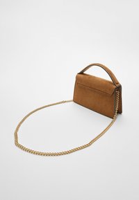 Brown suede handbag with a structured shape, front flap, and a gold chain strap. Features clean lines and minimalistic detailing.