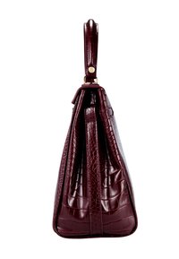 Sac à main en cuir texturé façon crocodile bordeaux foncé, avec une anse supérieure et des côtés structurés et plissés, vu de profil.