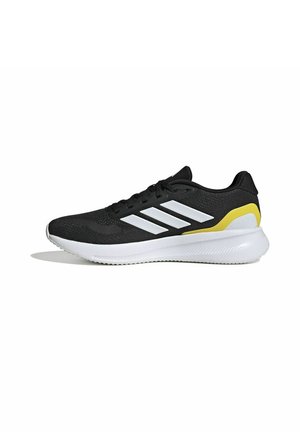 Scarpe sportive nere con tomaia in mesh grigio, tre strisce bianche, accento giallo vicino al tallone e suola bianca texturizzata.