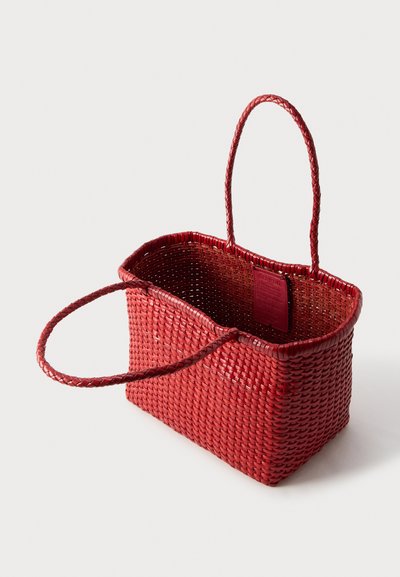 Ορθογώνιο κόκκινο υφαντό καλάθι tote με δύο πλεκτές λαβές και εμφανές ετικέτα μάρκας μέσα σε λευκό φόντο.