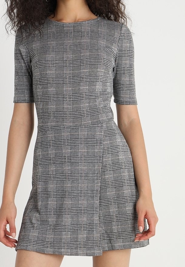 Vestido de manga corta con un patrón de cuadros en blanco y negro, que presenta un corsé ajustado y una falda acampanada. Hecho de tela texturizada.
