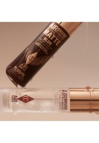 Two spray bottles: one dark brown with gold accents labeled "Matte Blur," the other clear with a metallic gold cap labeled "Setting Spray."