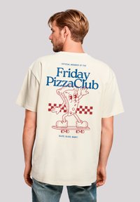 Cream-colored t-shirt featuring a playful pizza slice graphic on the back. Text reads "Friday PizzaClub" with checkered accents.