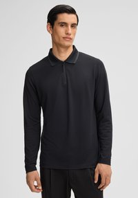 Polo shirt nero a maniche lunghe con colletto a mezza zip, realizzato in tessuto morbido con trama sottile e accenti di design minimalisti.