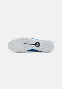 Shoe sole in white rubber with textured patterns, blue upper portion, and a black logo. Designed for grip and stability.
