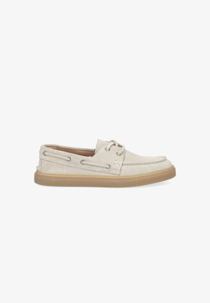 Chaussure bateau décontractée en suède beige clair avec fermeture à lacets sur le devant, surpiqûres moc toe, et semelle en caoutchouc tan, vue de côté sur fond blanc.