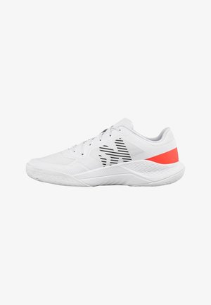 Zapatilla deportiva blanca con rayas negras en el lateral y un acento rojo brillante en el talón, suela texturizada y diseño con cordones, vista de lado.