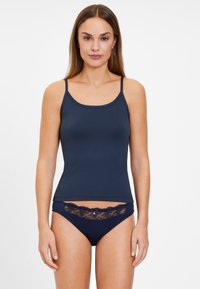 Marineblaue Baumwoll-Camisole mit dünnen Trägern, kombiniert mit passenden Slips, die Spitzenakzente und eine dekorative Schleife an der Taille aufweisen.