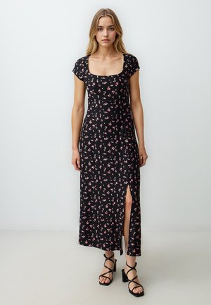 Zwarte maxi-jurk met bloemenpatroon, korte mouwen, vierkante halslijn en een zijsplit. Bevat roze bloemenpatronen en is gemaakt van lichtgewicht stof.