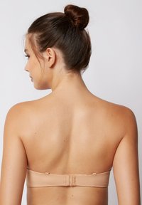 Nudes trägerloser BH mit glatter Textur, der über einen Verschluss im Rücken und ein minimalistisches Design verfügt und nahtlose Unterstützung bietet.