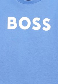 T-shirt in cotone blu con una grande stampa bianca della parola "BOSS" in lettere maiuscole grasse. Tessuto liscio, scollo rotondo.