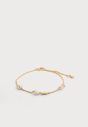 Delicada pulsera de cadena de oro que presenta tres perlas blancas irregulares y una pequeña cuenta ovalada de oro con cierre de langosta y extensión ajustable.