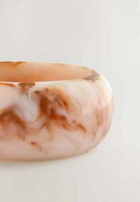 Translucent, lyserøde skål med virvlende brune mønstre. Glat overflade, rund form og en tykk kant. Materialet ligner harpiks.
