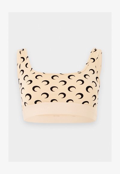 Μπεζ αθλητικό σουτιέν με φαρδιές τιράντες που έχουν επαναλαμβανόμενο μαύρο μοτίβο ημισελήνου και ελαστική ταινία στο κάτω μέρος.