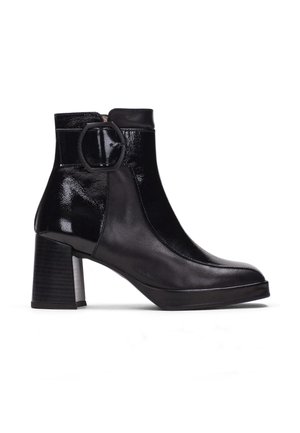 Bottine en cuir noir avec talon bloc et large boucle ronde sur le côté extérieur.
