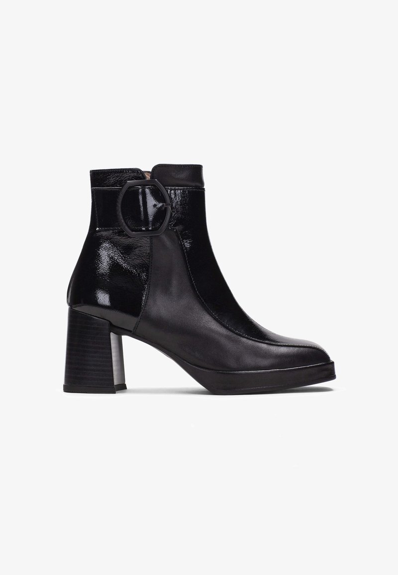 Bottine en cuir noir avec talon bloc et large boucle ronde sur le côté extérieur.
