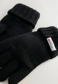 Gants tricotés noirs avec un poignet côtelé, présentant une texture douce et une étiquette indiquant une isolation "Thinsulate".