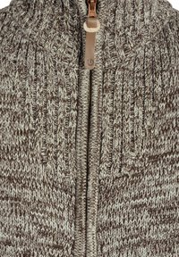 Strikket cardigan med høy krage, som har en blanding av brune og kremfargede nyanser, glidelås-lukking og ribbet tekstur gjennom hele plagget.