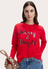 Czerwony sweter z napisem "Merry & Bright" wykonanym z cekinów. Miękka tkanina, okrągły dekolt, w komplecie torebka z cekinami. Swobodny krój.