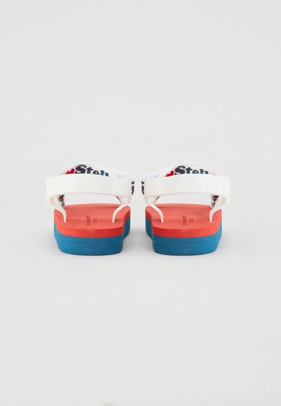 Sandalias blancas con suela estratificada que presenta secciones rojas y azules. Las correas tienen una marca y un acabado texturizado, ofreciendo un diseño casual.