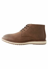 Botas de cuero marrón hasta el tobillo con punta redondeada, acentos cosidos y diseño de cordones; suela de goma con ribete en contraste ligero.