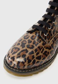 Stivali alla caviglia con stampa leopardata, finitura lucida, lacci neri e suola in gomma robusta, con dettagli di cucitura a contrasto lungo il bordo.