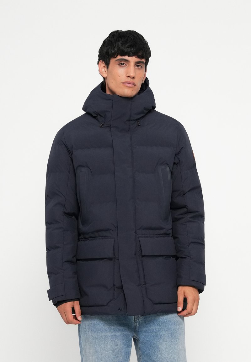 Navy blue puffer jacket with a high collar, zip and snap closure, front pockets, and elastic cuffs. Smooth texture, padded design for warmth.