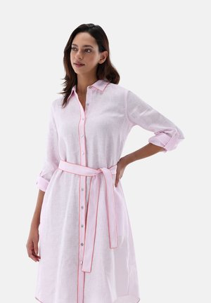 Abito in lino rosa chiaro con maniche lunghe, bottoni bianchi e una cintura rosa. Presenta piping rosa a contrasto lungo il colletto e le maniche.