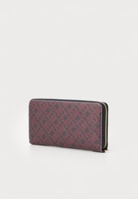 Zip-around wallet in dark red and black textured material, featuring a geometric pattern, with gold-toned zipper hardware.