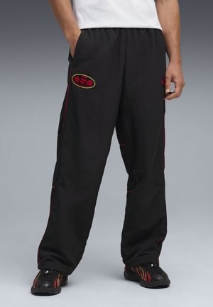 Czarne spodnie sportowe z czerwonymi akcentami, z naszywką z logo. Wykonane z lekkiego materiału, zaprojektowane z myślą o komforcie i ruchu.