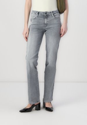 Hallux hallid denim teksad, kitsas lõige, viie taskuga disain, vöökohad ja kerge kulumise tekstuur, koos mustade kontsakingadega.