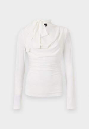 Λευκό στενό, μακρυμάνικο πουκάμισο με ντραπέ λαιμόκοψη και δεμένη φιόγκο στην αριστερή πλευρά.