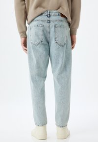 Jeans in denim blu chiaro con vestibilità rilassata, dotati di una vita media, due tasche posteriori e una leggera scoloritura uniforme.