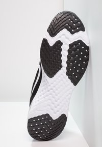 Černobílá podrážka sportovní obuvi s texturovanými vzory, vlnitými drážkami a mírným vyvýšením, navržená pro trakci a podporu.