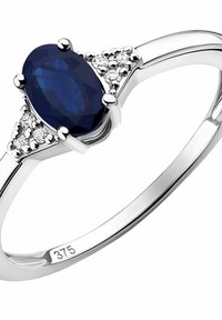 Anillo de gema ovalada azul engastado en plata pulida, con tres pequeñas piedras de acento a cada lado. Marcado con "375" por el contenido de oro.