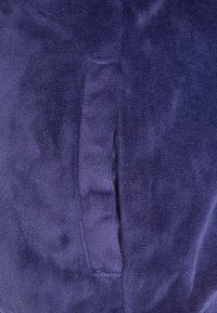 Navy modrý fleece mikina s měkkým, texturovaným povrchem. Obsahuje přední kapsu, která je nenápadně začleněná do designu.