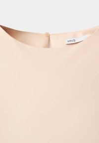 Hellbeiger Kleid-Ausschnitt mit kleinem Knopfverschluss und sichtbarem MNG-Markenlabel im Kragen.