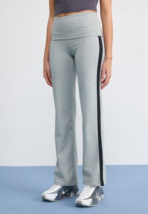 Light gray stretchy pants with a wide waistband and a black side stripe, paired with reflective silver athletic shoes.