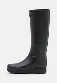 Botte de pluie en caoutchouc noir avec une finition lisse, tige haute, semelle texturée pour une meilleure adhérence et un léger plateau pour un peu de hauteur supplémentaire.
