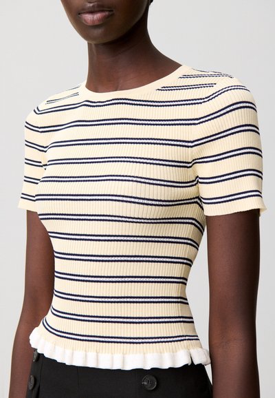 Top de manga corta acanalado en crema con rayas marinas, con bajo con volantes y silueta ajustada. Textura suave y escote redondo clásico.