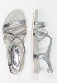 Sandali glitterati argento con più cinturini, una soletta in suede grigio morbido e una suola bianca testurizzata con un motivo a zigzag.
