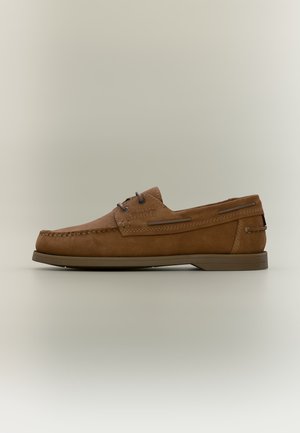 Brun læder moccasin-stil loafer med syninger og en slank gummisål, vist i sideprofil på en neutral baggrund.